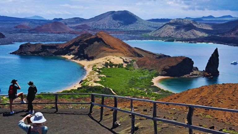 Visitors enjoying the stunning view of Pinnacle Rock in Galápagos, with pristine beaches and volcanic landscapes.